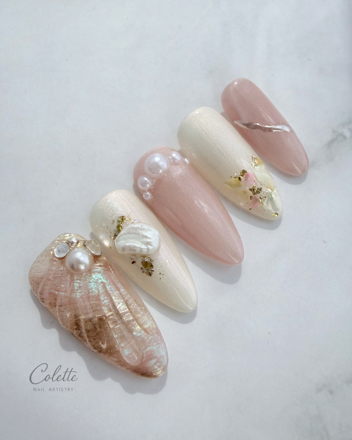 Close-up of Pearl Mist press-on nails with pearl, shell and iridescent details in soft pink and ivory tones.