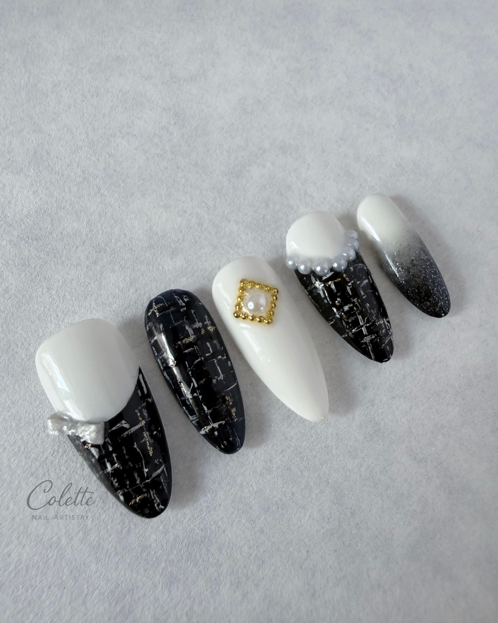 Tweed Glow press-on nails in black and white with textured tweed detailing, 3D bow and pearl accents.