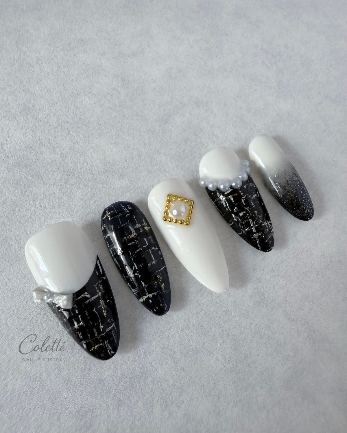 Tweed Glow press-on nails in black and white with textured tweed detailing, 3D bow and pearl accents.